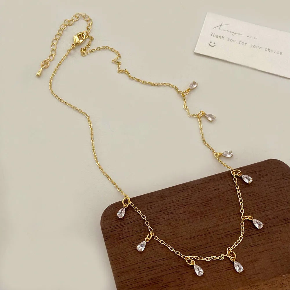Women's zircon jewellery set showing geometric pendant necklace, matching earrings, and anklet on a white background.