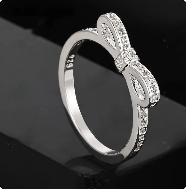 Silver bow-shaped ring with crystal rhinestones on finger