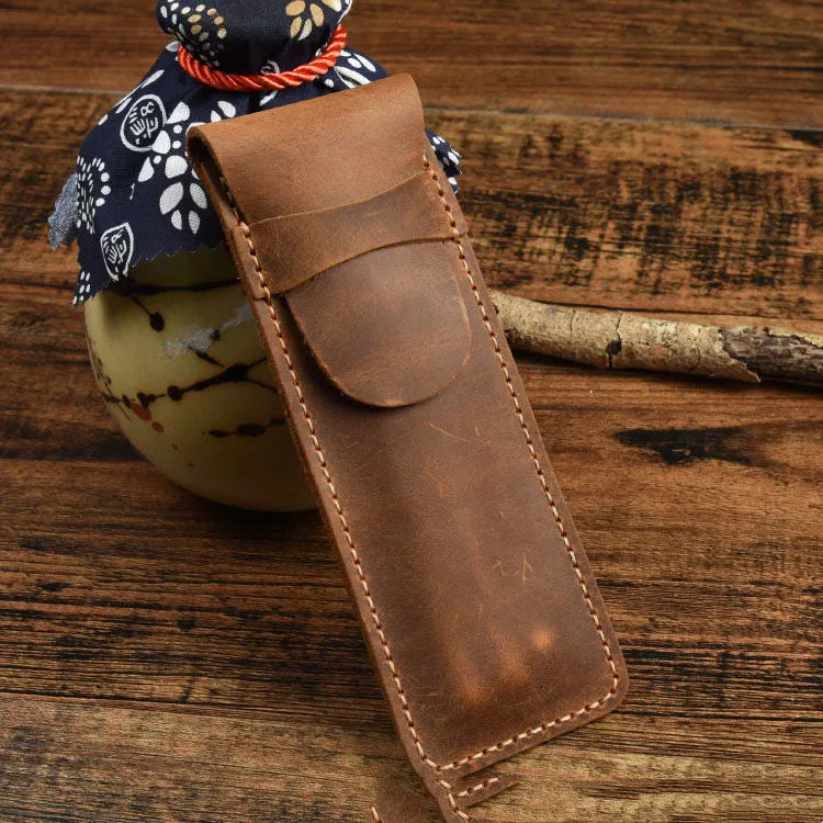 Brown leather pencil case with zip opening on a plain background