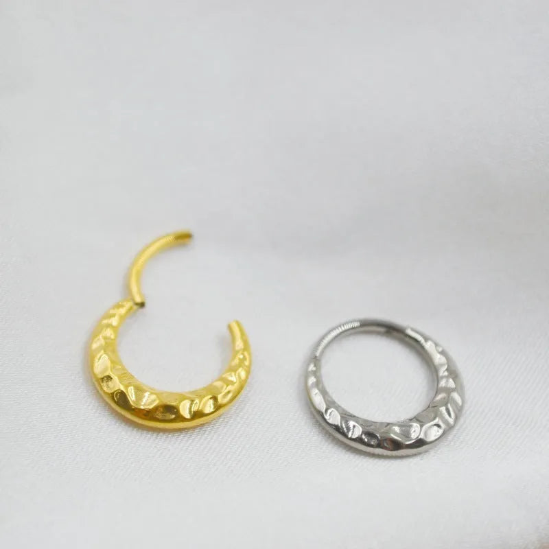 Close-up of a titanium concave-convex nose ring in gold finish, showing its textured profile and 1.2mm thickness.