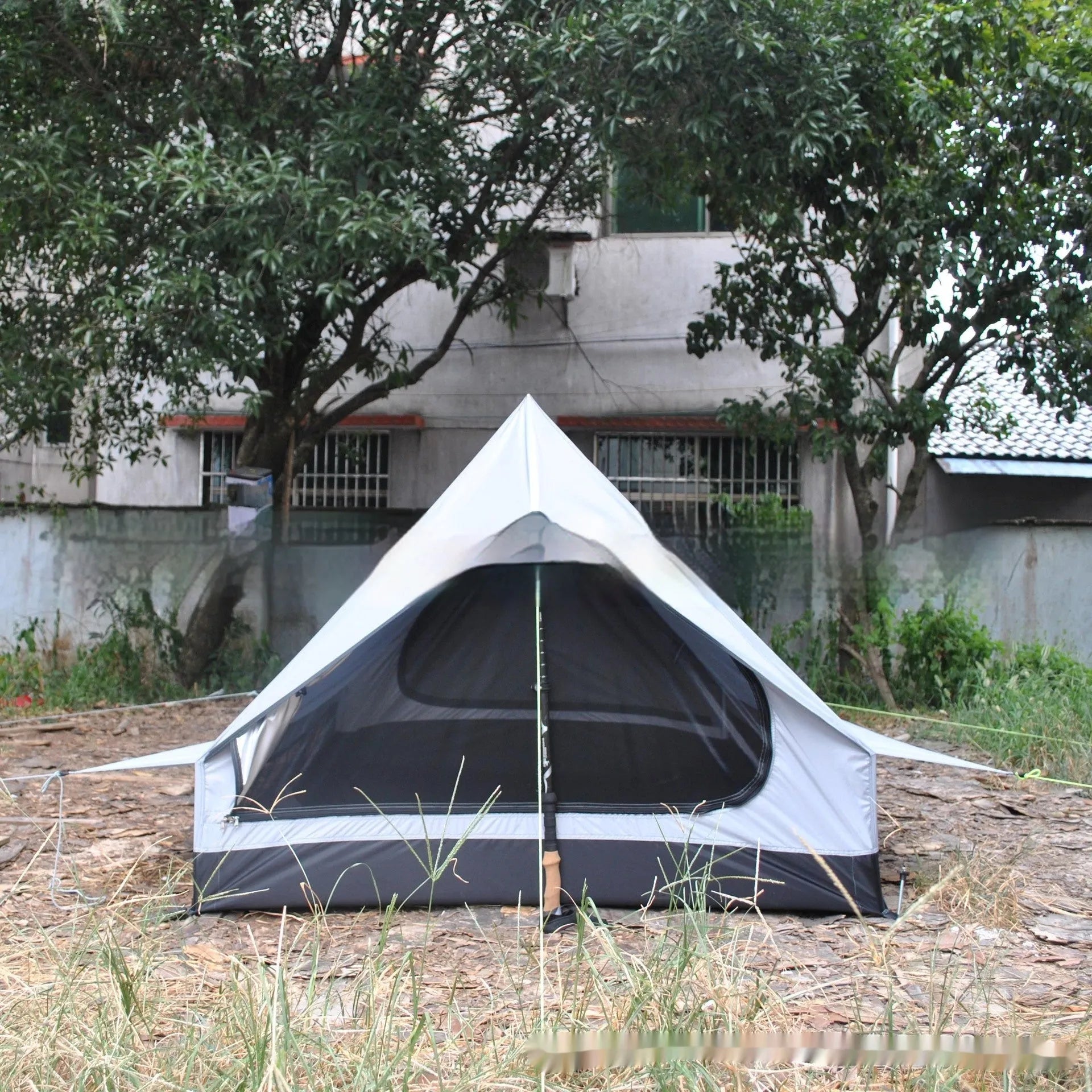 Brown or white A-line hiking tent pitched using hiking canes, showing spacious interior for 2-3 people.