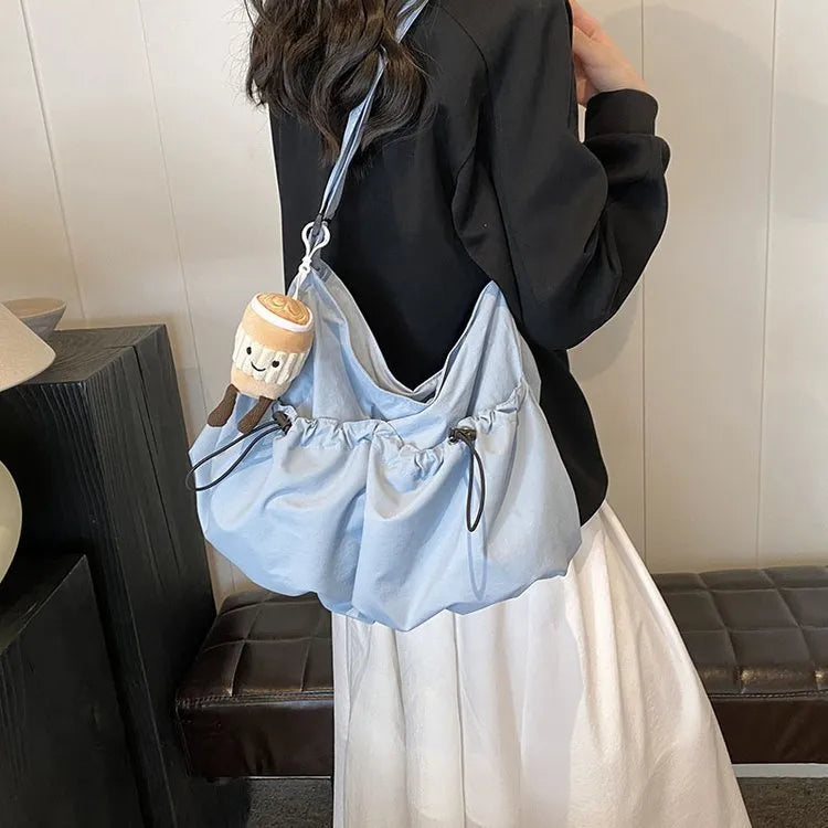 Green pleated crossbody student bag showing foldable polyester construction and internal mobile phone pocket