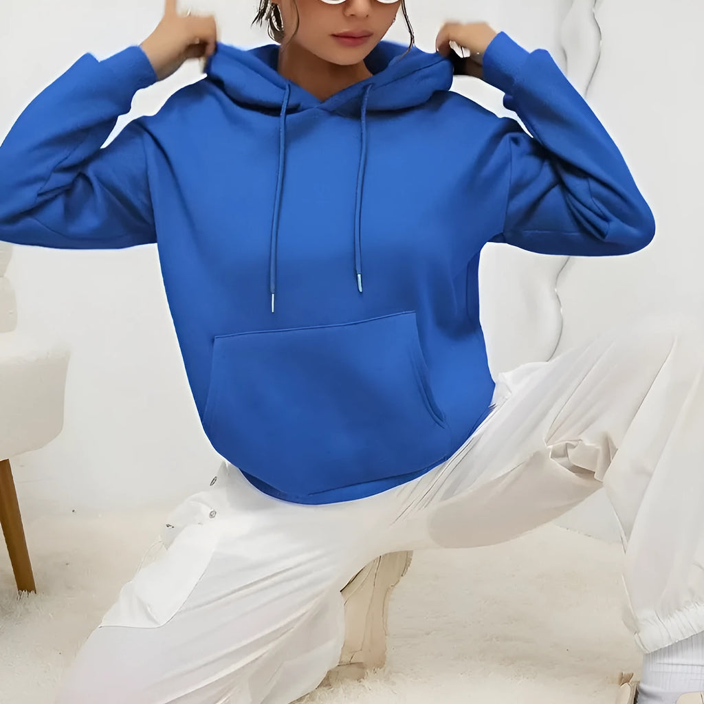 Woman wearing a loose-fitting black hooded sweatshirt with a front kangaroo pocket.