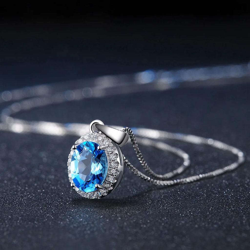 Four-piece 925 sterling silver jewellery set with blue topaz gemstones in a geometric design, showing earrings, ring, pendant and necklace.