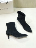 Black pointed toe women's ankle boots with stiletto heels on a neutral background.