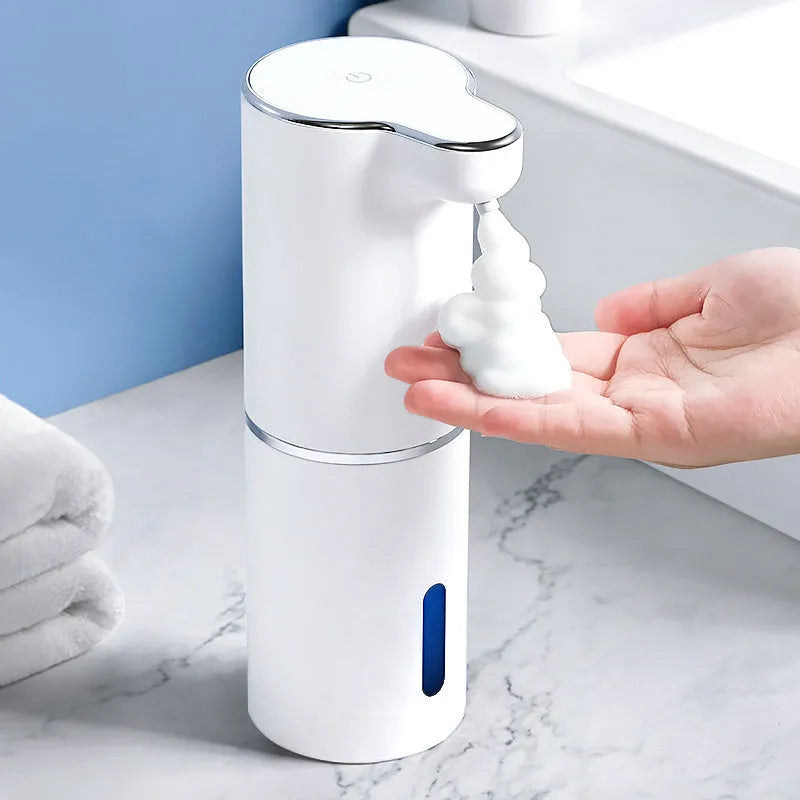 White ABS automatic sensor soap dispenser on countertop with USB cable, dispensing foam hand sanitiser.