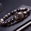 Close-up of a women's adjustable bracelet with a dark obsidian fox bead and sliding knot.