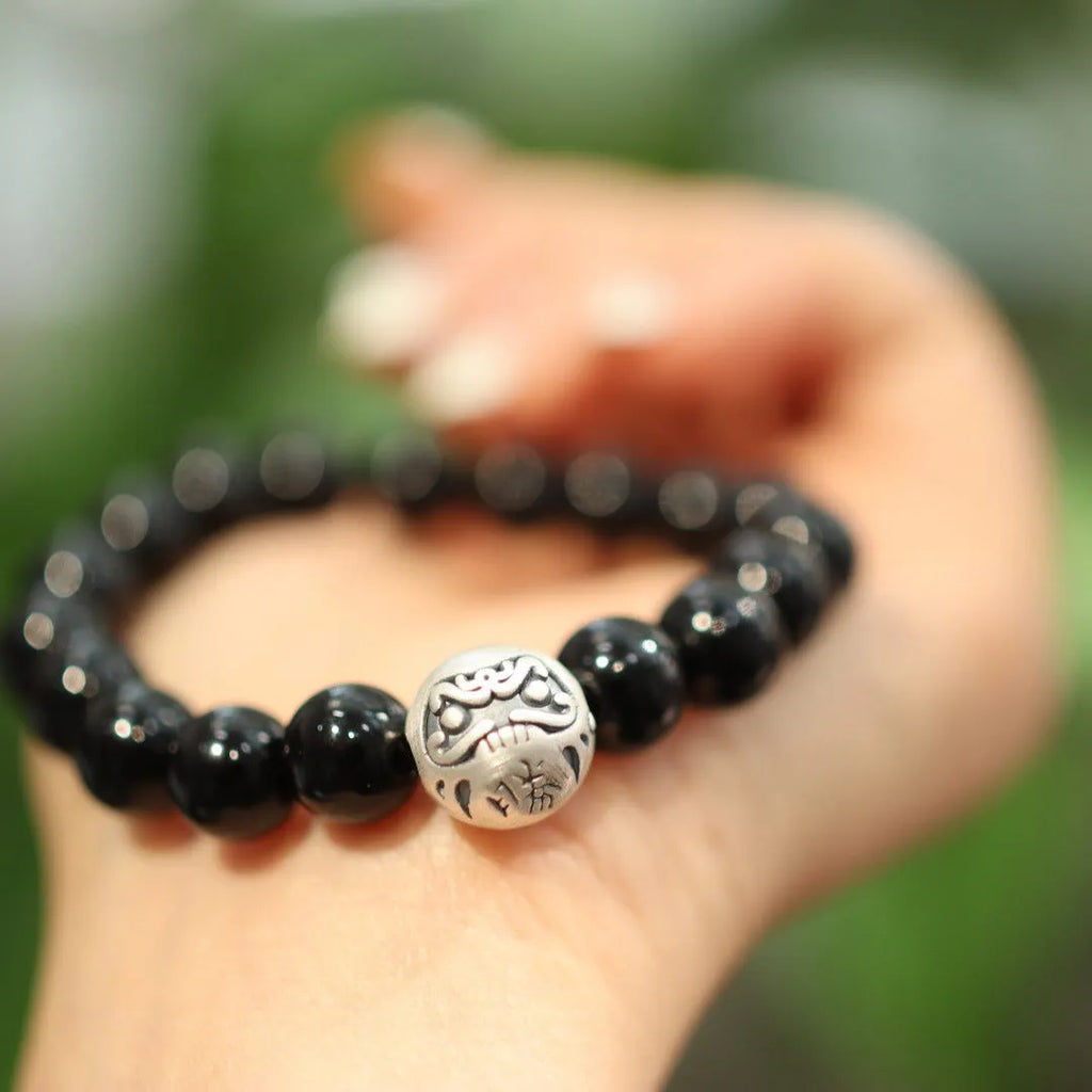 Close-up of a women's bracelet with large 10mm black agate beads and sterling silver details on a wrist.