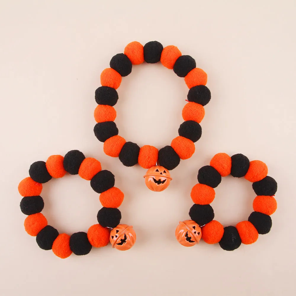 Orange Halloween cat collar with 'Naughty Cat' text and a detachable plastic pumpkin charm on a table.