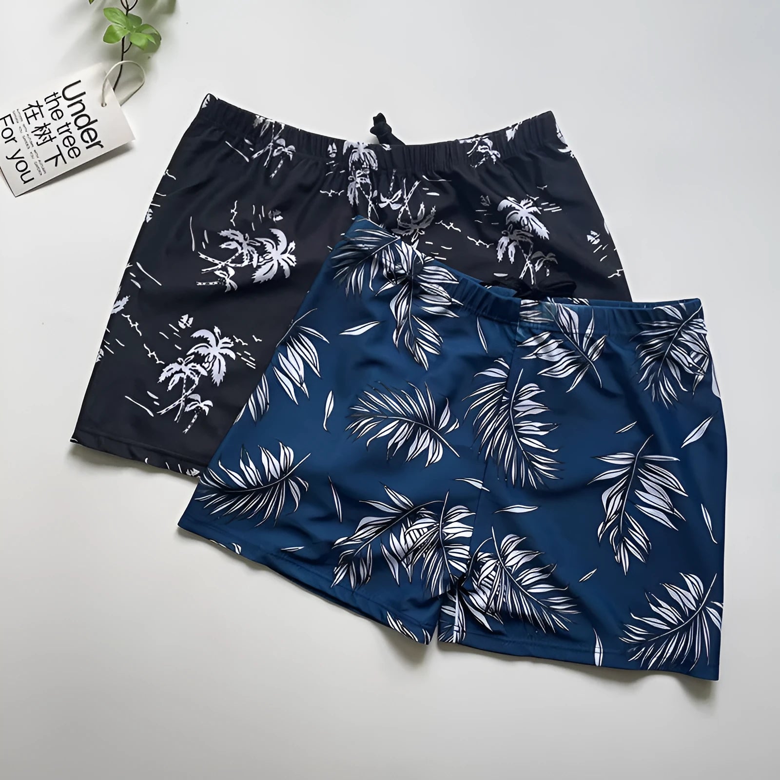Men's loose-fit polyester swim trunks in dark blue with large flower print, three sizes available
