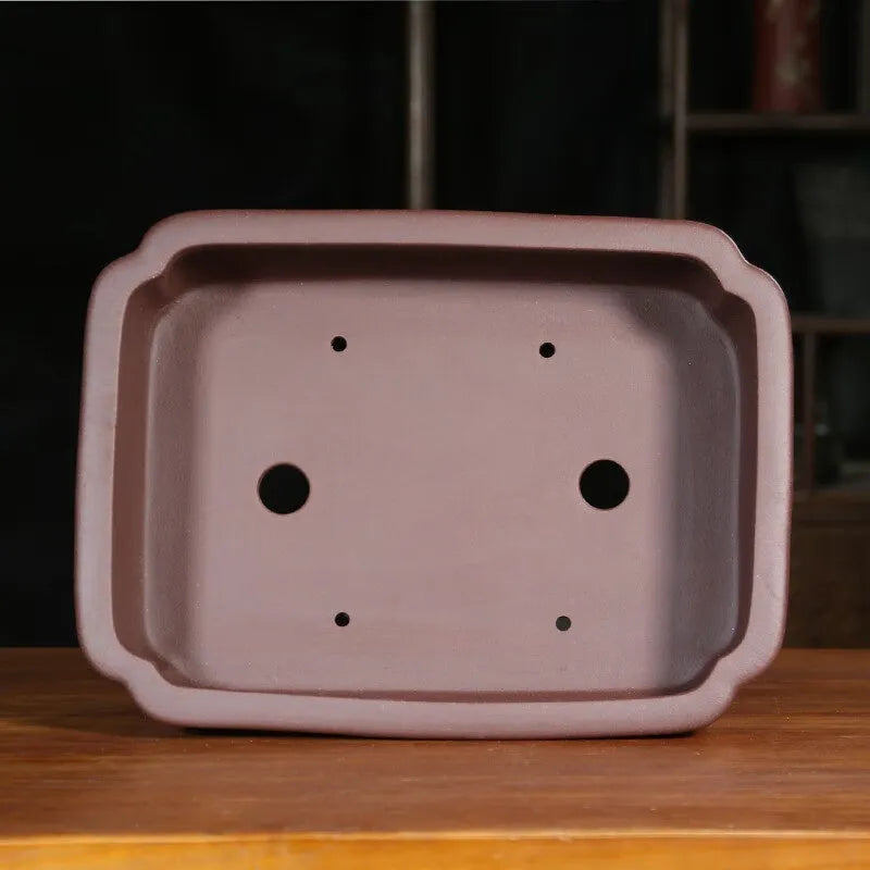 Rectangular antique purple sand bonsai planter with corner-cut design on floor.