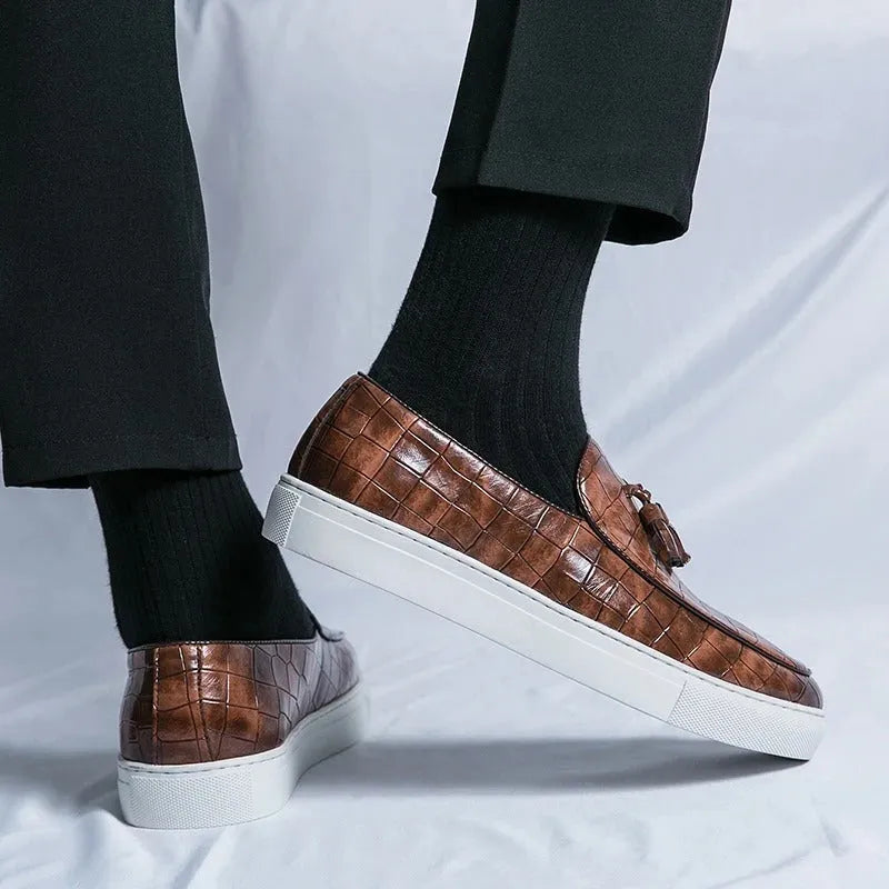 Men's black tassel slip-on sneakers with a round toe and rubber sole on a white background.