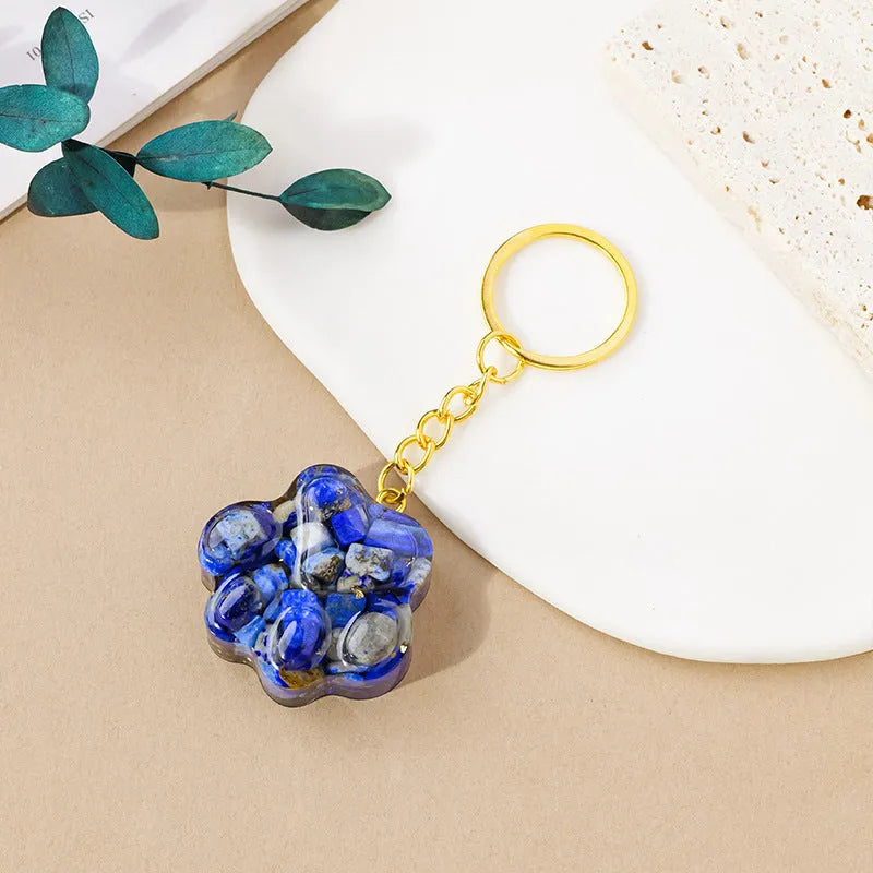 Small natural crystal cat's paw charm on a keyring, showing colour options including pink, red, blue, and purple gemstones.
