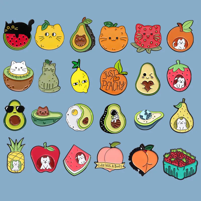 Colourful cartoon fruit and letter design metal brooch on a fabric background.