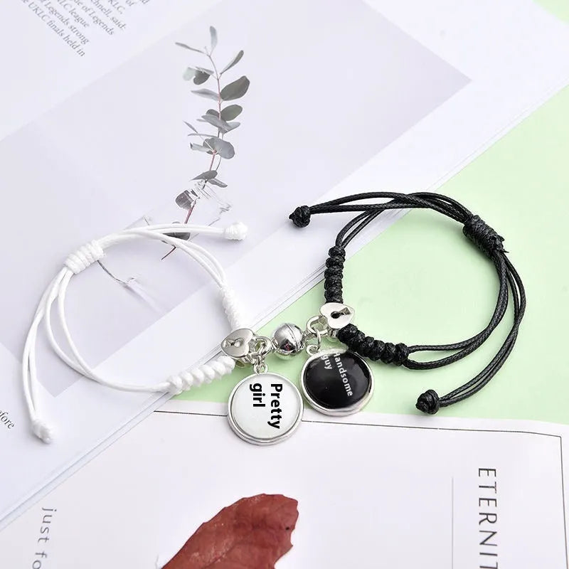 Pair of magnetic suction bracelets with alloy charms in various love and friendship themed designs on a wrist.