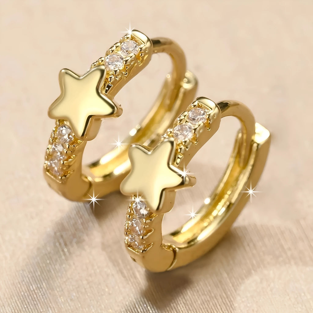 Gold copper five-pointed star earrings with inlaid zircon stones on a neutral background