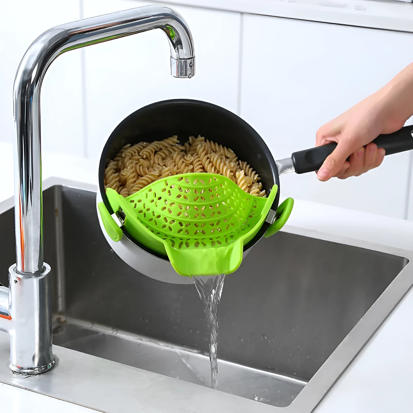 Silicone pot side drain stopper in black attached to saucepan rim with leak-proof edge