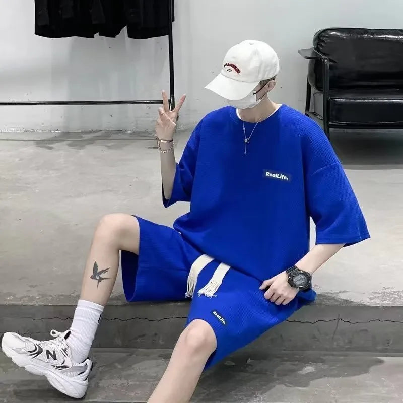 Man wearing a grey waffle-textured short sleeve top and matching shorts leisure set.