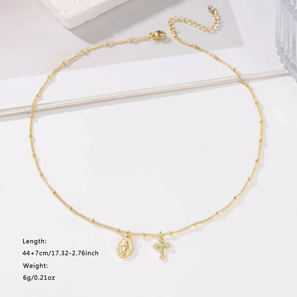 Gold-coloured geometric Virgin Mary and cross pendant necklace on a chain.