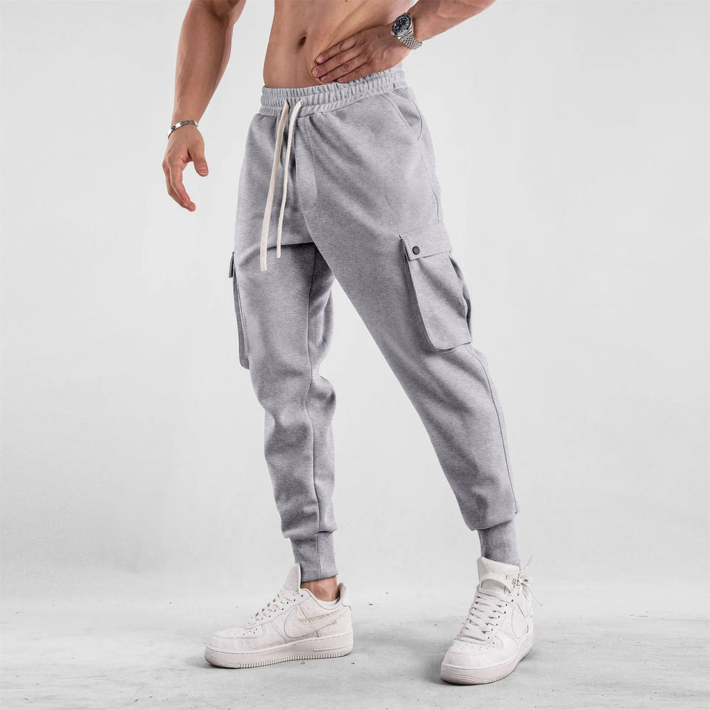 Men's loose-fit light grey cotton sports trousers with ankle tie and side pockets.