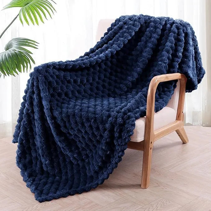 Soft camel-coloured plaid fleece blanket for children folded on a bed.