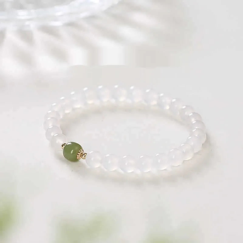 Handmade white agate and cinnabar bracelet with text design on a wrist.