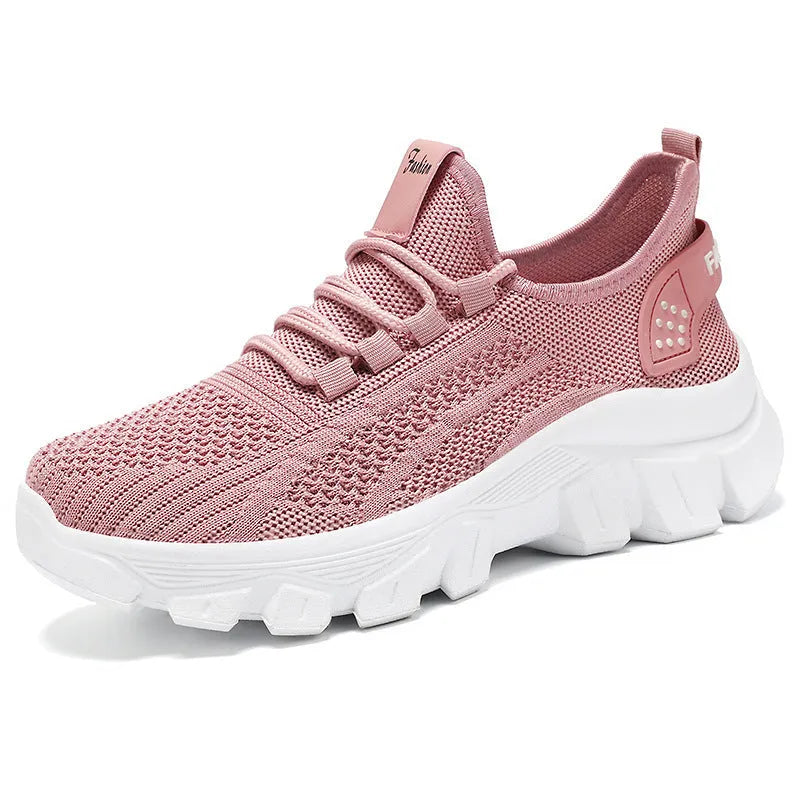 Women's white Flyknit running sneakers with round toe, flat heel, and thick PVC sole on a light background.