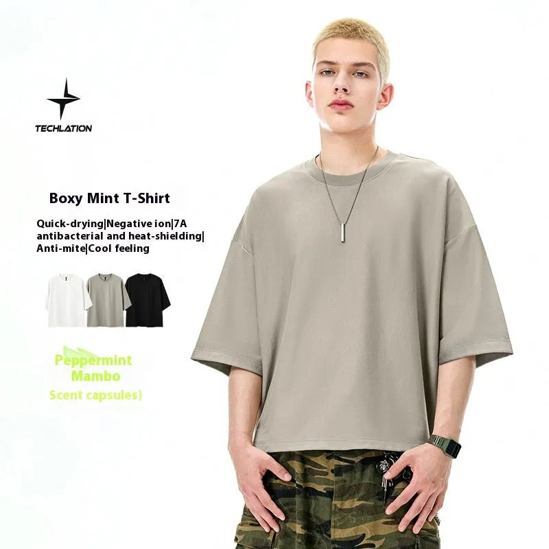 Man wearing a sand gray loose-fitting short sleeve pullover top.
