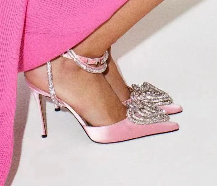 Women's pink satin sandal with heart-shaped rhinestone detail on pointed toe and adjustable ankle strap.