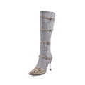 Grey women's knee high boots with a thin high heel and pointed toe on a plain background.