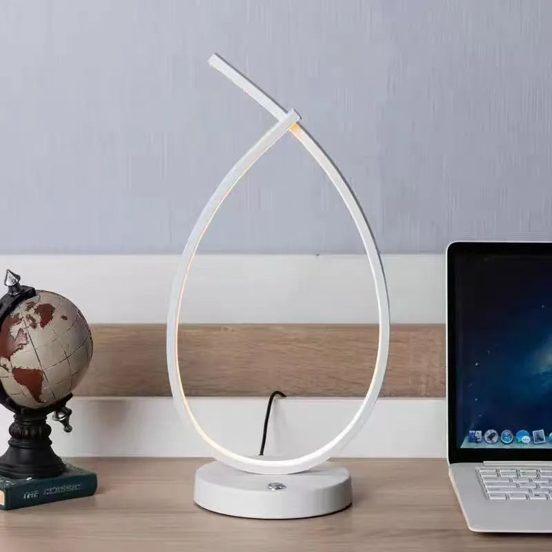 Black and white drop-shaped USB table lamp on a wooden desk.