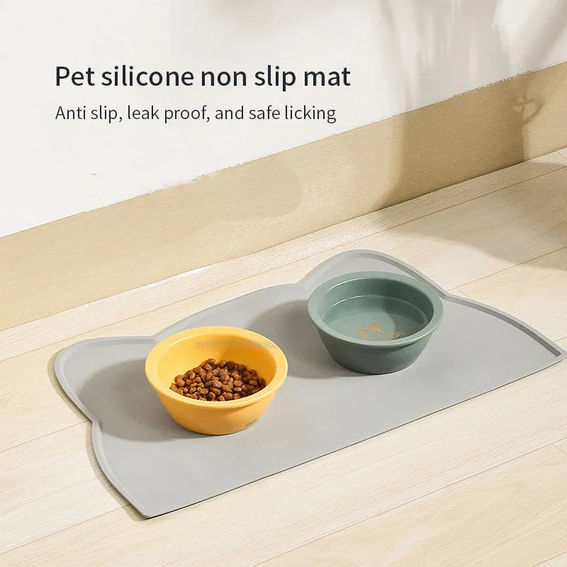 Blue silicone cat head-shaped pet feeding mat on a wooden floor.