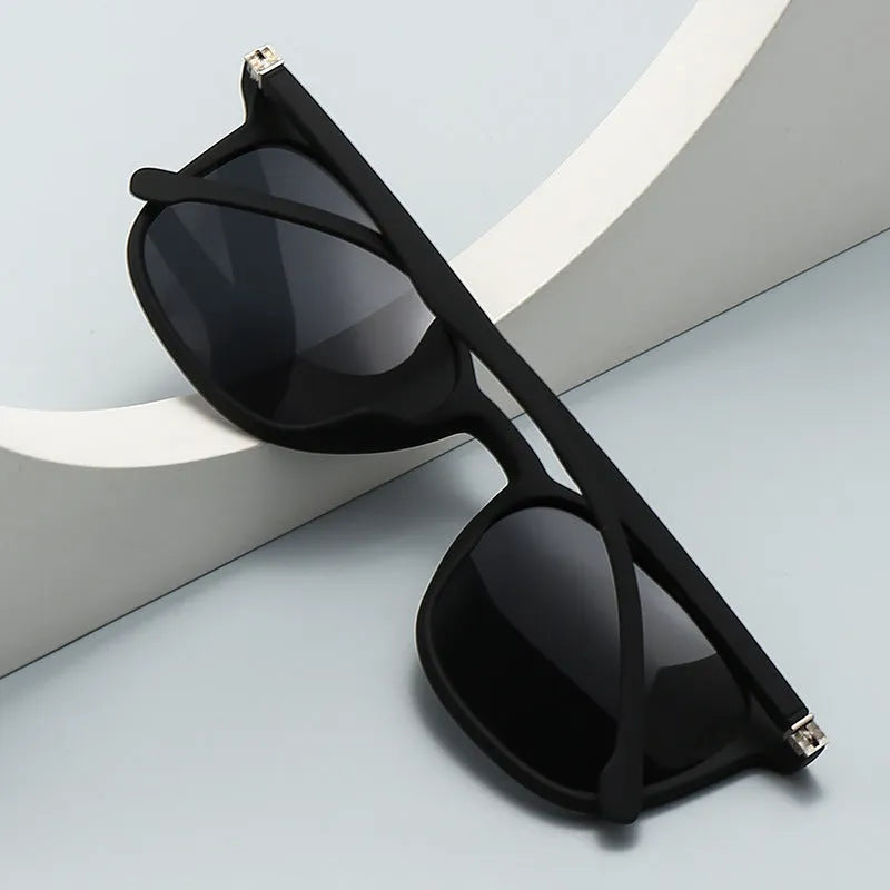 Men's polarised sunglasses with a black frame and dark green lens, showing PC construction and elastic paint finish.