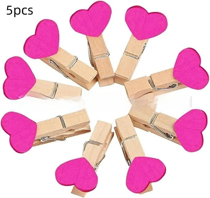 Set of five solid wood heart-shaped clips in different colours on wooden surface