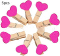 Set of five solid wood heart-shaped clips in different colours on wooden surface