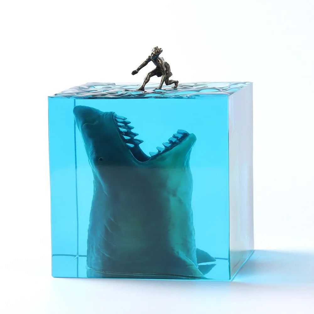 Close-up of a crystal resin shark surfer night light ornament on a dark surface.