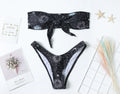 Black bikini print one-piece swimsuit with a split tube top and backless design.