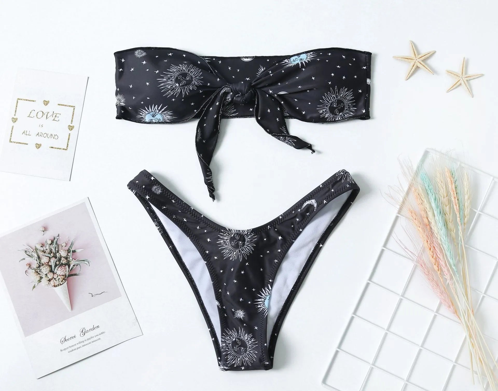 Black bikini print one-piece swimsuit with a split tube top and backless design.