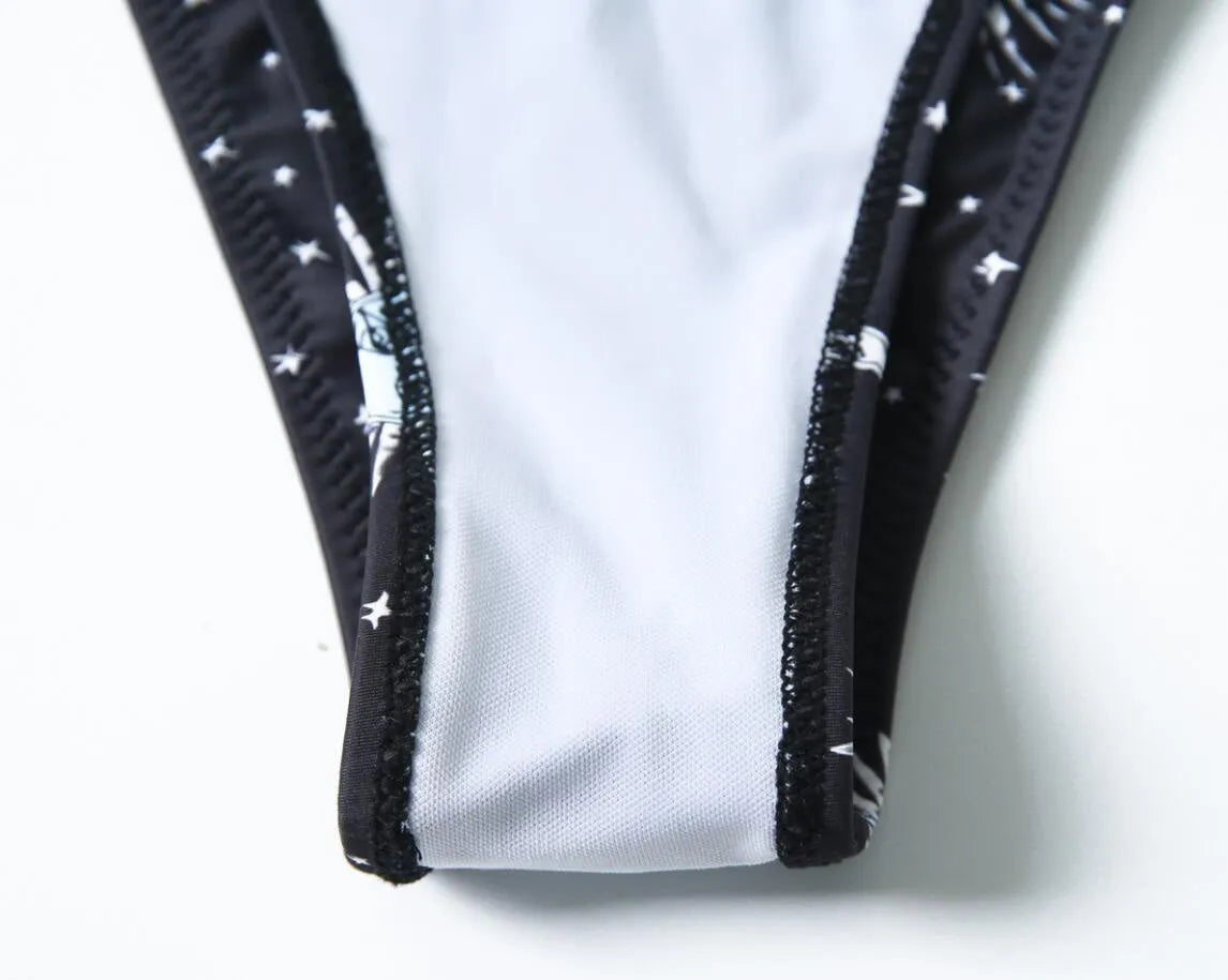 Black bikini print one-piece swimsuit with a split tube top and backless design.