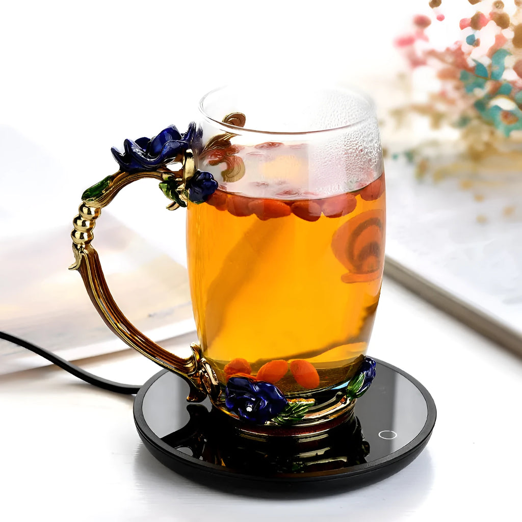 Black circular coffee mug warmer with a tempered glass surface on a desk.