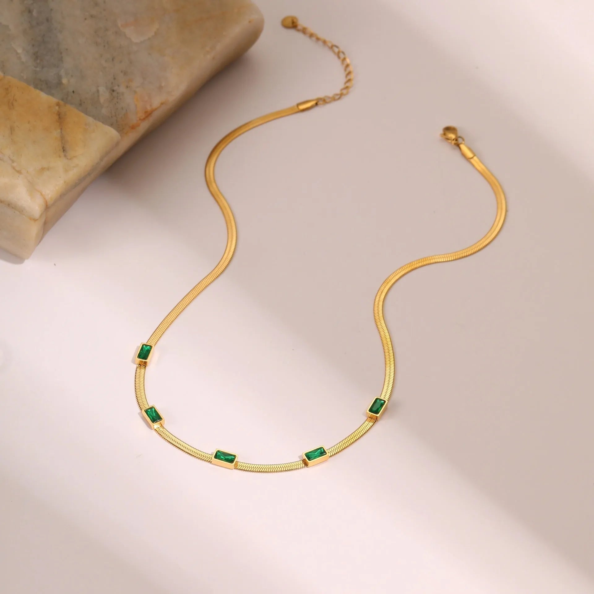 Geometric square zircon pendant on a flat stainless steel snake chain necklace in a gold colour finish.