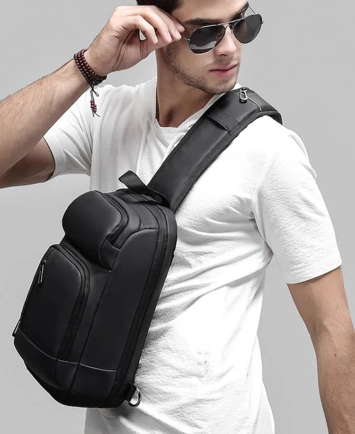 Black PVC outdoor shoulder bag showing medium size, shoulder strap, and internal pocket organisation