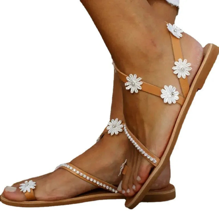 Brown women's Roman-style sandals with flat rubber sole and white floral decoration on the upper.