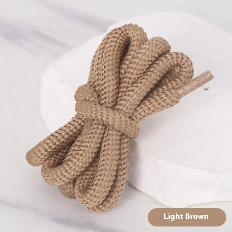 Oval cross-section shoelace adapter rope in various colours, shown next to a trainer and sweatshirt.