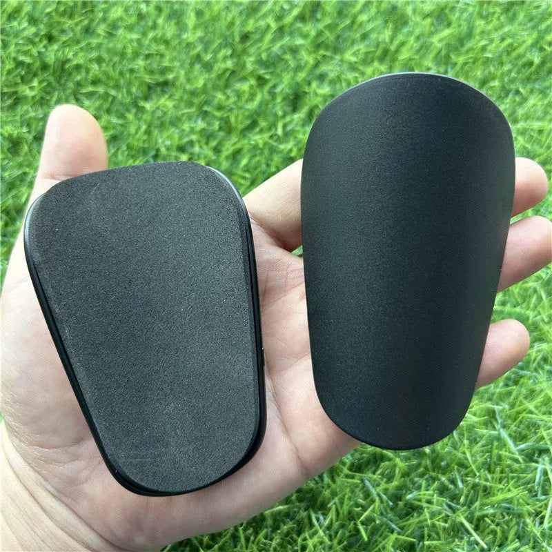 Extra small mini football shin guards in black and white colours measuring 8cm by 5cm