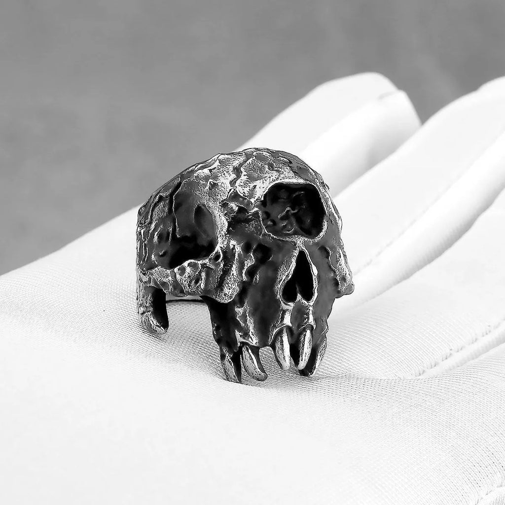 Close-up of a silver-toned alloy ring with a raised one-eyed skull design on a black background.