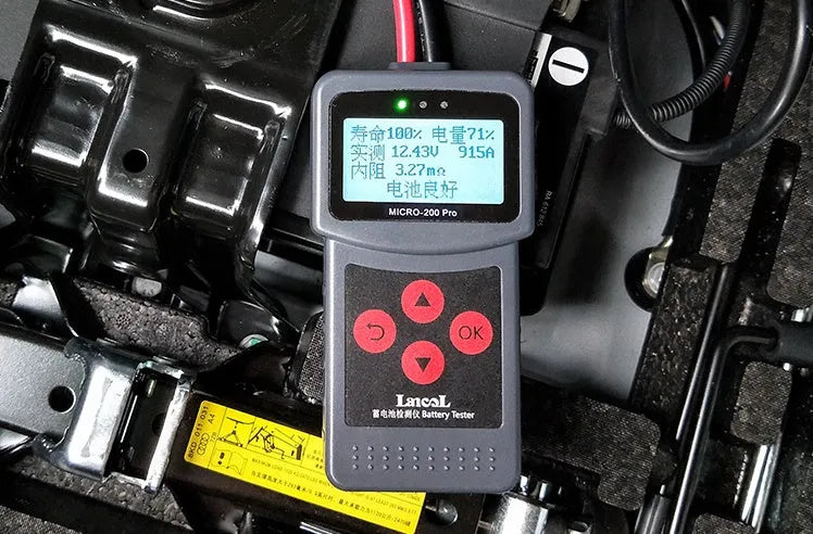 Black car battery tester with digital display measuring internal resistance on a workbench