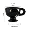 Hand-pinched irregularly shaped ceramic mug in a solid colour, shown on a table.