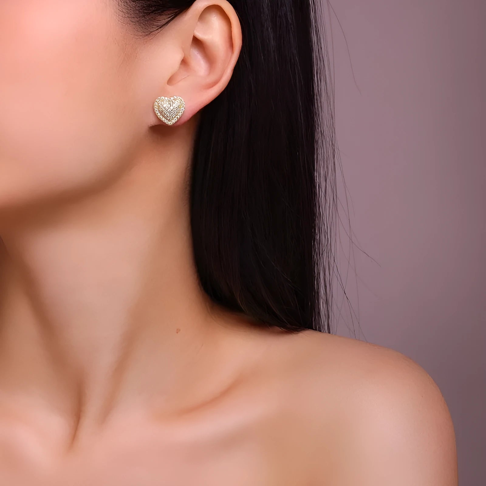 A pair of gold-colour heart-shaped stud earrings with a moissanite stone, on a plain background.