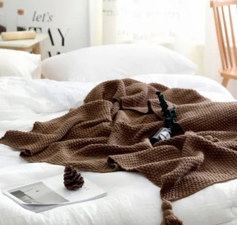 Fringed acrylic knit ball blanket 130x170cm in beige on a sofa